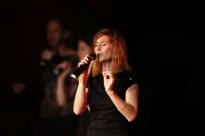 Woman holding a microphone and singing, with eyes closed