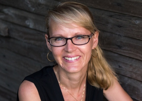 Upper torso of woman in glasses smiling 