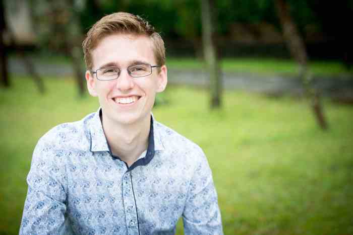 Upper body shot of young man with glasses, smiling